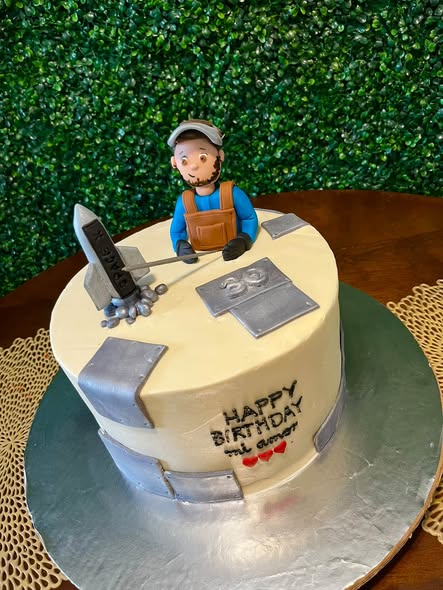 Cream-colored birthday cake with a sculpted welder, silver panels, a number 30, and a personalized birthday message